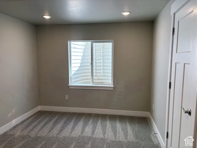 Room featuring neutral wall tones, recessed lighting, carpeted flooring, and a sliding window with an integrated egress well