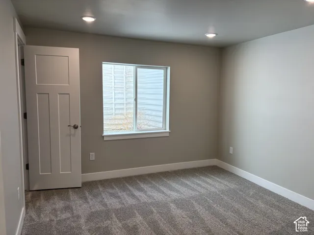 Neutral-toned room featuring wall-to-wall carpeting, recessed ceiling lighting, and a single-panel interior door