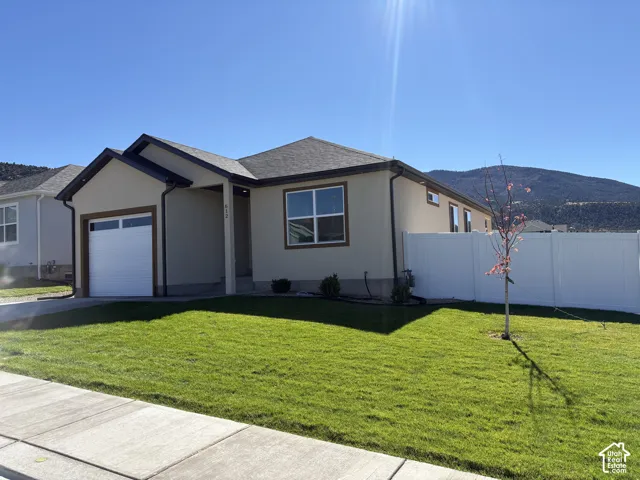 Single-story residence featuring a neutral stucco exterior, a single-car garage, and white vinyl perimeter fencing