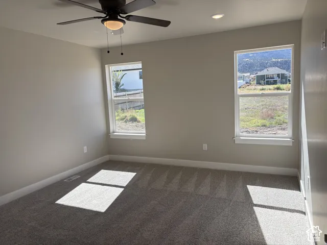 Neutral wall tones, carpeted flooring, two double-hung windows, recessed lighting, and a ceiling fan with integrated light fixture
