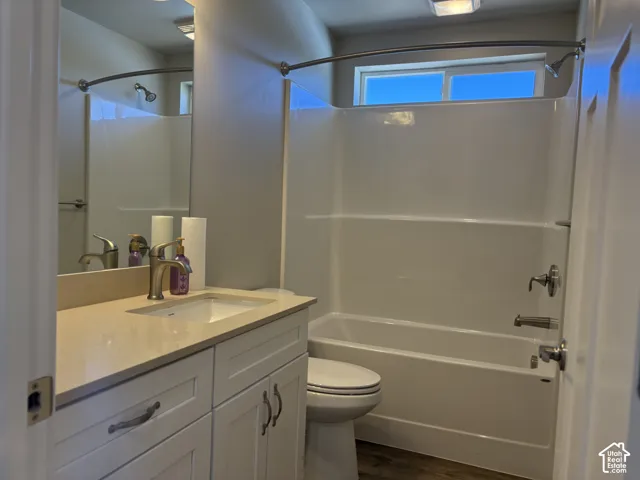White shaker-style vanity with a solid surface countertop, rectangular undermount sink, brushed nickel faucet, large wall-mounted mirror, and a tub-shower combination with a curved shower rod