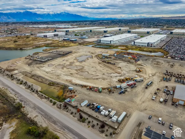 Aerial perspective of expansive industrial lot featuring mountain backdrop, waterfront border, and direct road access