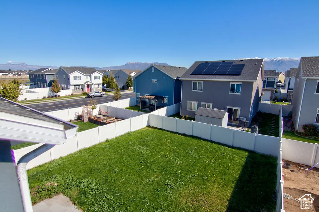Rear yard featuring a vinyl privacy fence, lawn area, and mountain backdrop