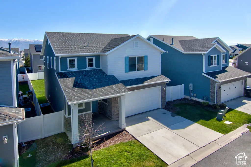 Two-story exterior featuring composite siding, stone veneer accents, a covered front porch with square columns, and a concrete driveway