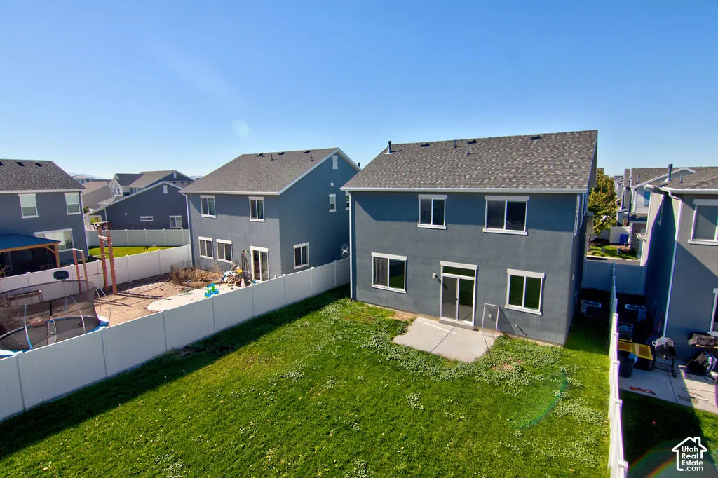 Rear exterior featuring a concrete patio, sod lawn, and full-height vinyl privacy fencing