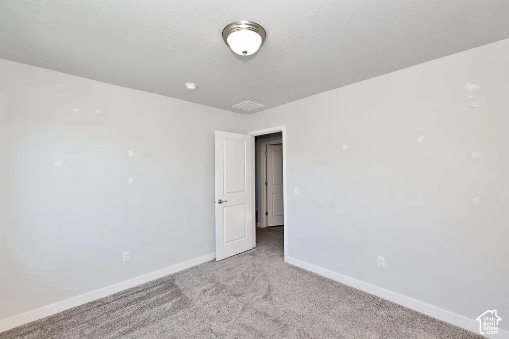 Room featuring neutral-toned carpeting, a brushed nickel flush-mount light fixture, and a solid-core interior panel door