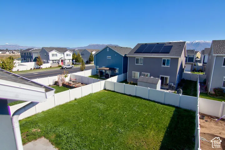 Rear yard featuring a vinyl privacy fence, lawn area, and mountain backdrop