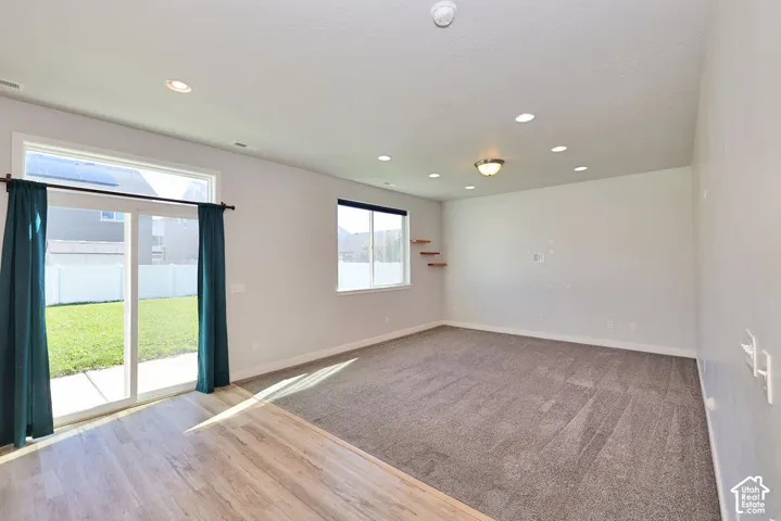 Neutral-toned interior featuring recessed lighting, wood-finish flooring, wall-to-wall carpeting, sliding glass doors, and dual-pane windows