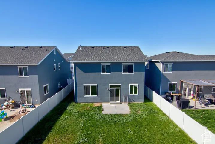 Two-story residence featuring a concrete rear patio, white vinyl perimeter fencing, and asphalt shingle roofing