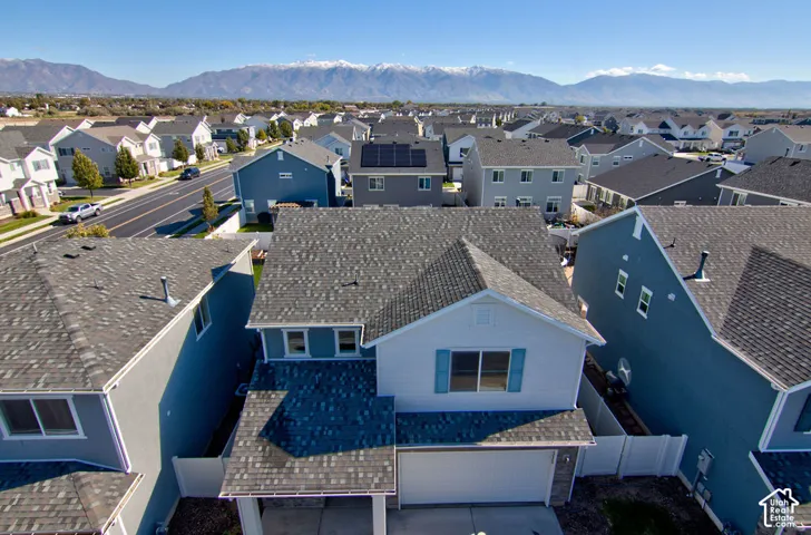 Two-story residence featuring composite shingle roofing, horizontal siding, attached two-car garage, white vinyl perimeter fencing, and prominent mountain backdrop
