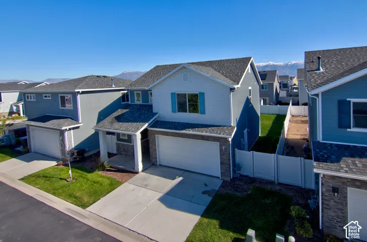 Two-story residence featuring a mixed-material exterior of horizontal siding and stone veneer, a two-car garage, a covered front entry, and a fenced backyard