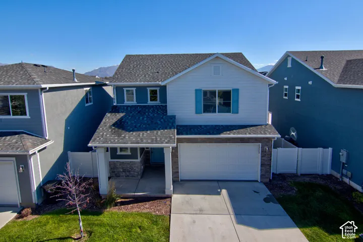 Two-story residence featuring a mixed-material facade of stone veneer and horizontal siding, decorative shutters, an attached two-car garage, a covered front entryway, and asphalt shingle roofing