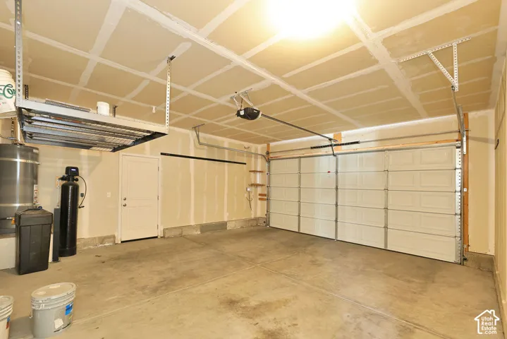 Multi-car garage featuring a sectional overhead door, concrete flooring, overhead ceiling-mounted storage rack, and water filtration system