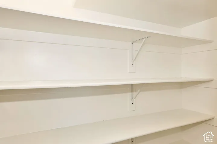 Built-in storage featuring tiered white shelving and white metal support brackets on shiplap wall paneling