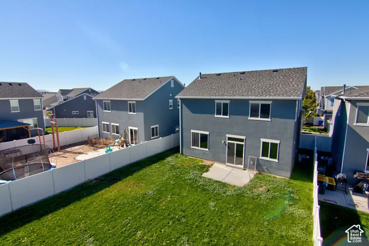 Rear exterior featuring a concrete patio, full-height white vinyl privacy fencing, and a grass lawn
