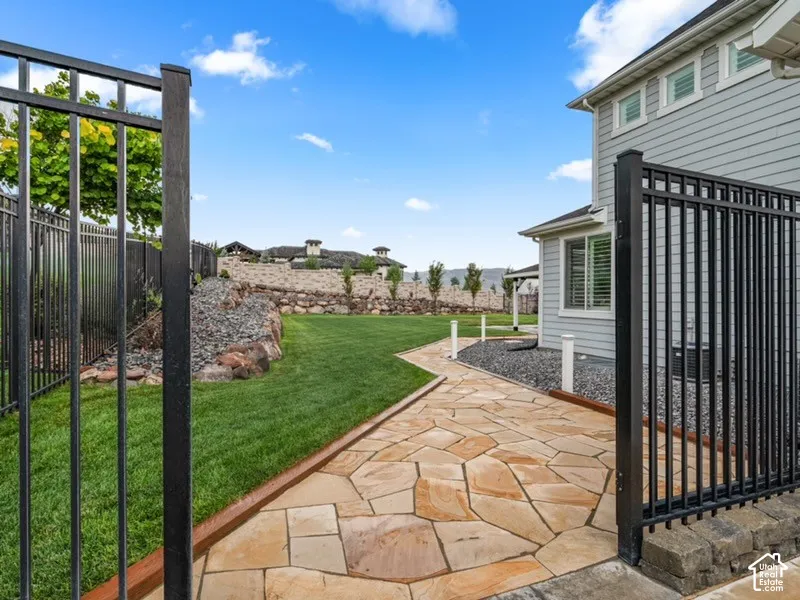 Expansive backyard oasis featuring manicured lawn, mature landscaping, and tiered hardscaping with natural stone patio