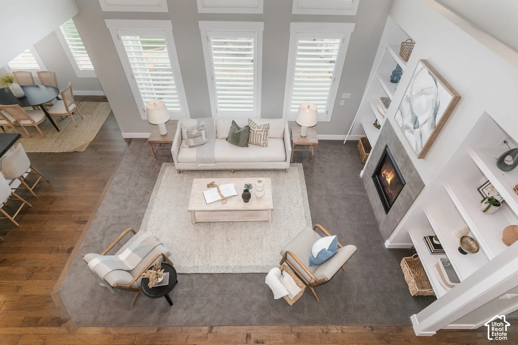 High ceilings with tall windows, plantation shutters, built-in shelving, and a stone-surround fireplace