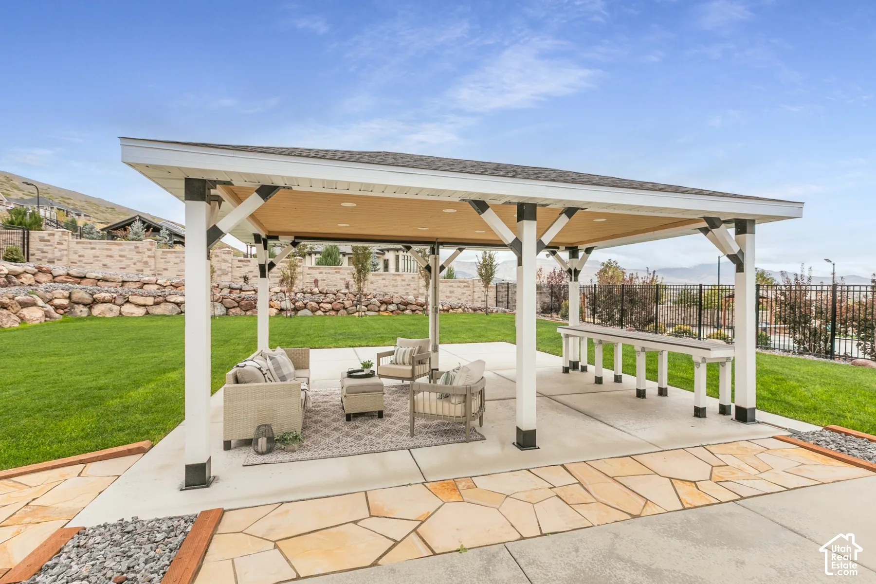 Covered outdoor pavilion featuring a built-in stone-top bar, recessed lighting, concrete patio, and flagstone hardscaping
