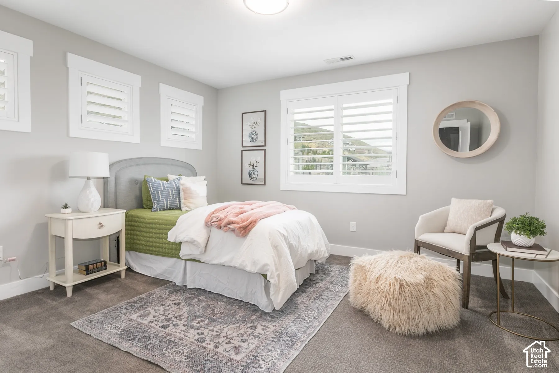 Neutral-toned interior featuring plush carpeting, expansive windows with custom plantation shutters, and trim-detailed window casing