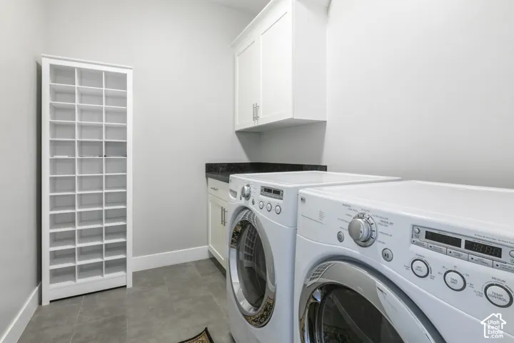 Laundry area featuring built-in floor-to-ceiling cubby shelving, upper and lower cabinetry, stone-finish countertops, and tile flooring