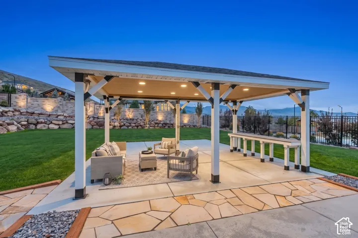 Covered outdoor pavilion featuring a built-in bar, recessed lighting, concrete patio, and stone masonry landscape wall