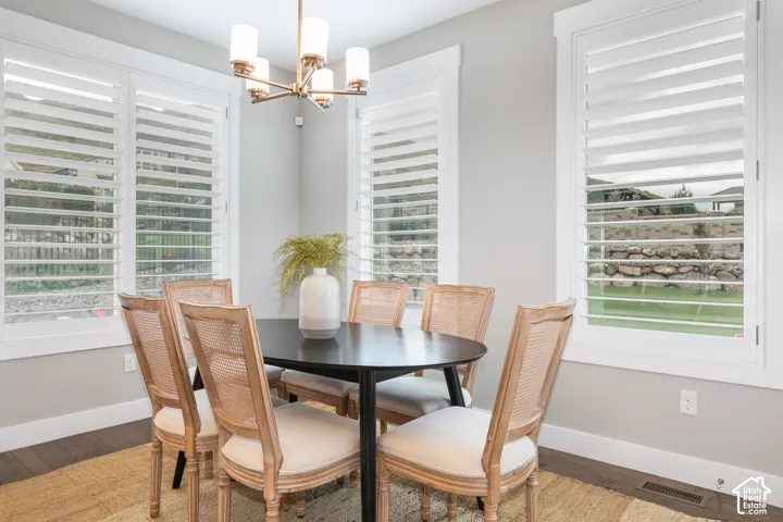 Light-filled area featuring wood-finish flooring, multi-pane windows with white plantation shutters, and a brass-tone multi-arm pendant light fixture