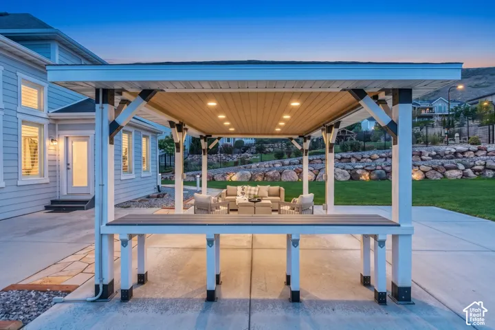 Covered outdoor pavilion featuring a built-in bar, recessed ceiling lighting, a concrete patio, and stacked-stone retaining walls
