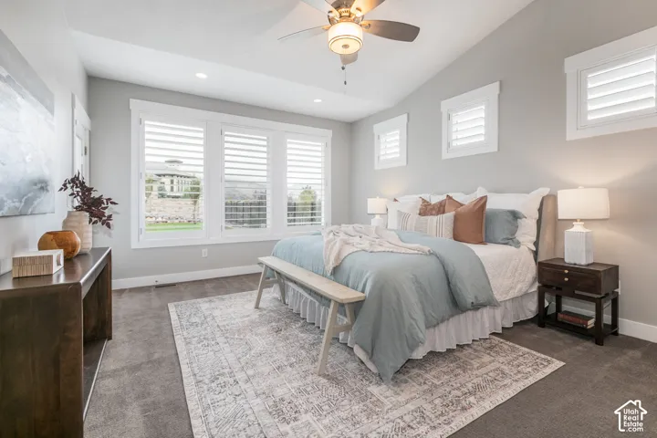 Vaulted ceiling featuring a central lighted ceiling fan, expansive triple-pane window array, and plantation shutters