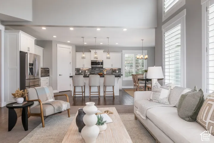 Open-concept area featuring high ceilings, wood-finish flooring, recessed lighting, and white cabinetry with a kitchen island