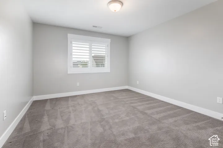 Neutral-toned interior space featuring wall-to-wall carpeting, white plantation shutters, and a flush-mount ceiling light fixture