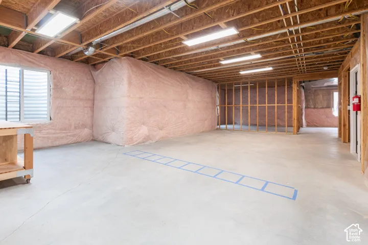 Unfinished lower level featuring exposed wood joist ceilings, concrete flooring, insulated wall paneling, and LED strip lighting