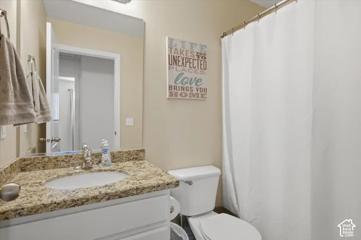 Full bathroom featuring a white vanity with a stone countertop, undermount oval sink, chrome faucet, and a wall-mounted mirror