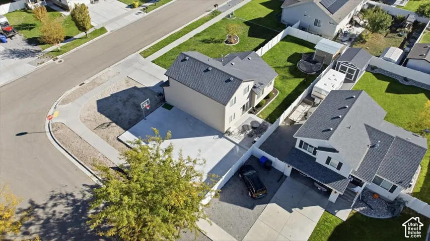 Aerial perspective of a two-story residence featuring a concrete driveway, enclosed backyard, and storage structure
