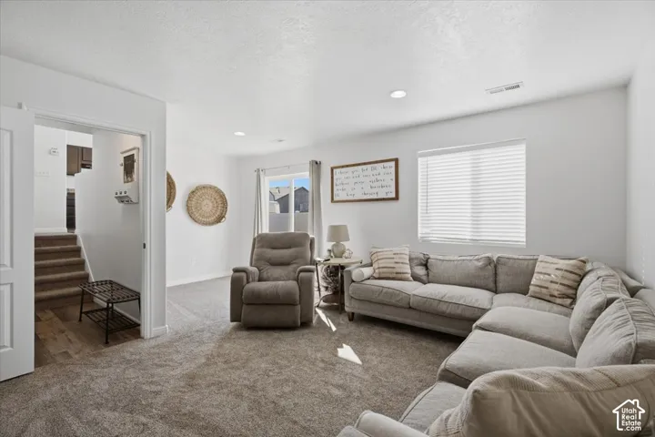 Neutral-toned carpeting, recessed lighting, and large windows with horizontal blinds