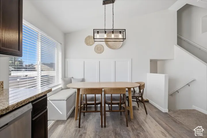 Built-in white bench seating, custom board-and-batten wall detailing, linear metal-frame pendant lighting, wood-finish flooring, and natural light from expansive windows