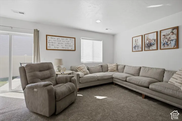 Living area featuring neutral carpeting, recessed ceiling lighting, a sliding glass door, and window blinds