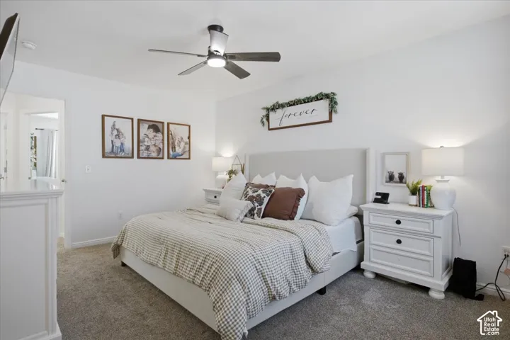 Neutral-toned carpeting, ceiling fan with integrated lighting, and white walls