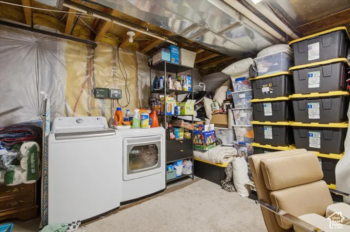 Utility area featuring a washer and dryer set, exposed floor joists, and wall-mounted electrical components