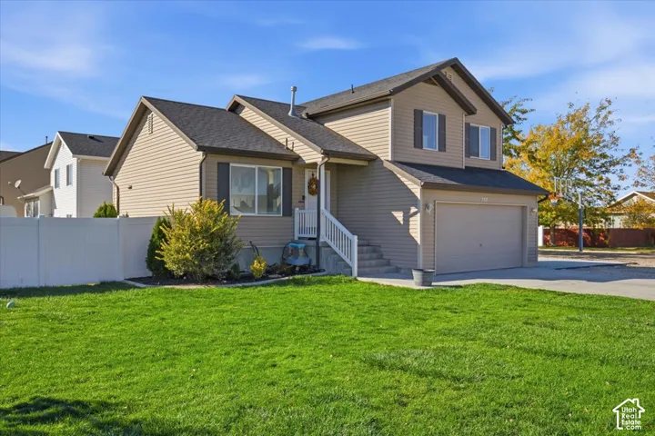 Two-story residence featuring horizontal vinyl siding, an attached two-car garage, white vinyl privacy fencing, and a concrete driveway