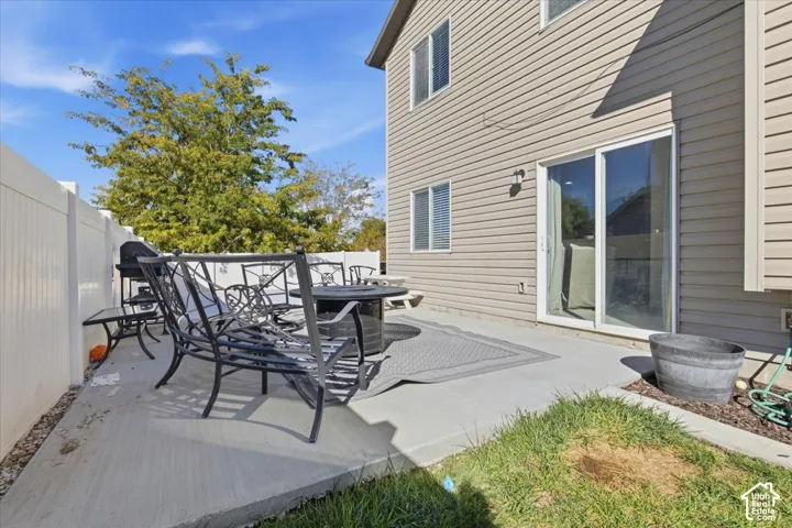 Concrete patio featuring horizontal vinyl siding, sliding glass doors, and a white privacy fence