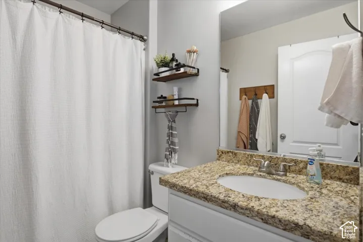 Bathroom featuring a stone-look countertop with an integrated oval sink, white cabinetry, a full-length wall mirror, and built-in tiered wall shelving