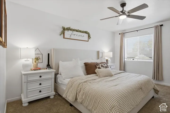 Neutral-toned carpeting, window with slatted blinds, and ceiling fan with integrated light fixture