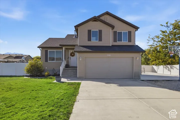 Two-story exterior featuring tan horizontal siding, attached two-car garage, asphalt shingle roof, and concrete driveway