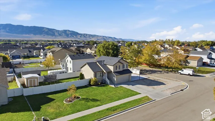 Two-story residence featuring a paved driveway, attached garage, white vinyl perimeter fencing, and a sodded lawn