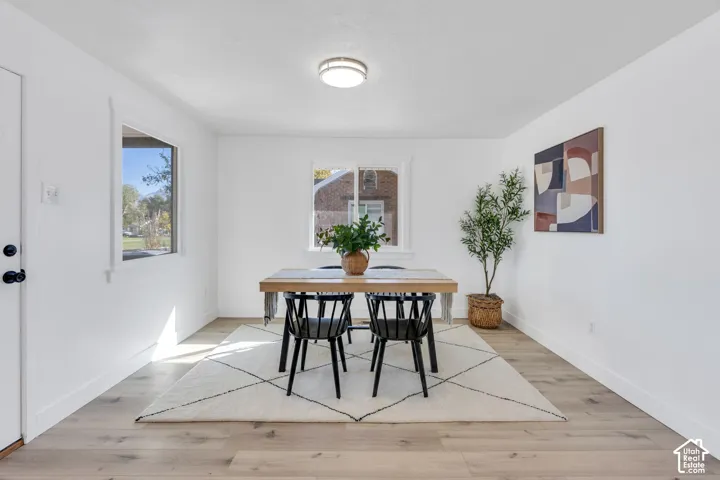 Bright interior space featuring wood-finish flooring, crisp white walls, dual windows, and a flush-mount circular ceiling fixture