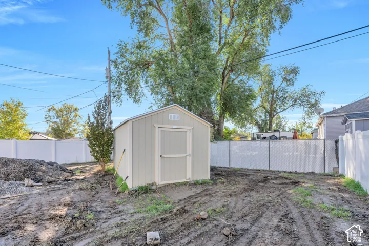 Backyard featuring a shed with light-colored siding and white vinyl perimeter fencing