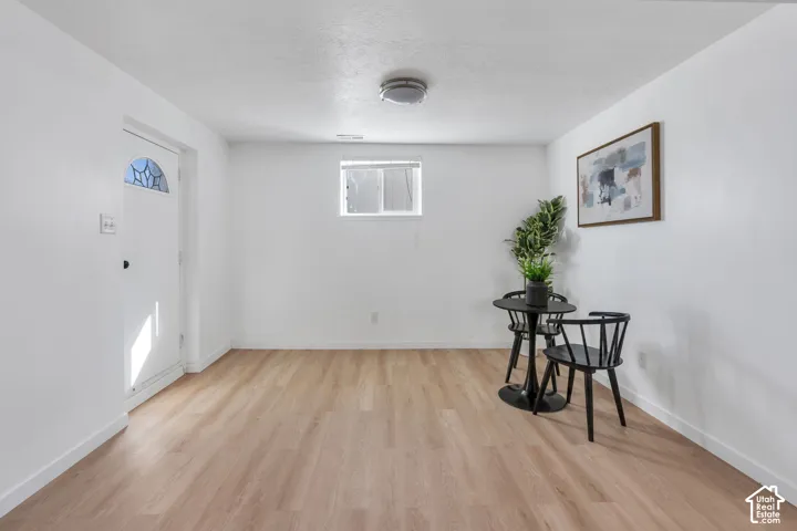 Neutral-toned interior space featuring light wood-finish flooring, a white exterior-style door with decorative glass inlay, and a flush-mount ceiling light fixture