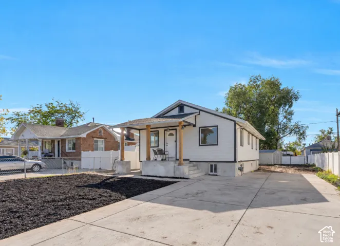 Single-story residence featuring white horizontal siding, a covered front porch with timber posts, concrete foundation, and an expansive concrete driveway