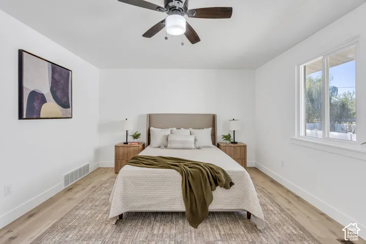 Neutral-toned interior featuring wood-finish flooring, a multi-blade ceiling fan with integrated lighting, and a dual-pane horizontal sliding window