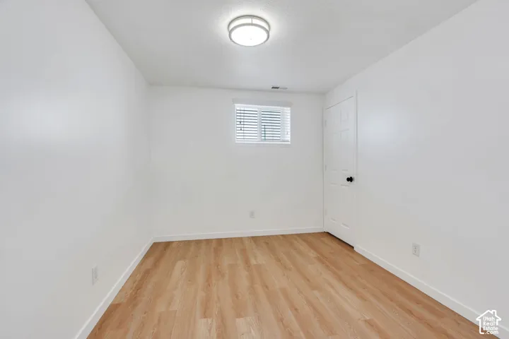 Room featuring wood-finish flooring, a neutral color palette, a single-panel window, and a ceiling-mounted light fixture